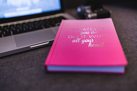 Pink notebook with a silver laptop and a camera thumbnail