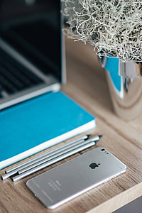 Silver iPhone with a blue notebook and pencils thumbnail