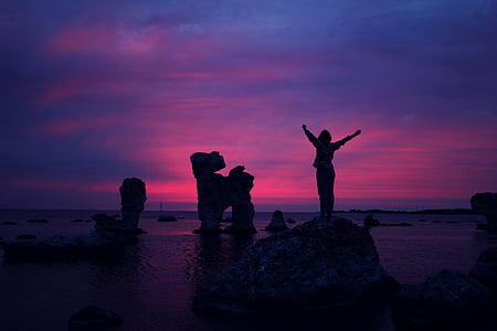 person standing on rock in front of body of water thumbnail
