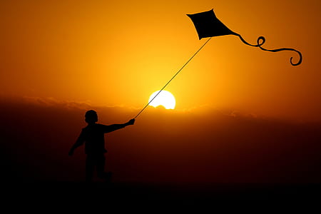 silhouette of child playing kite thumbnail