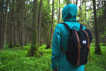 person wearing green hoodie and black backpack standing on forest during daytime photo thumbnail