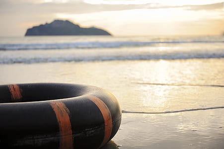 selective focus photo of a black flotation device on black sand beach thumbnail