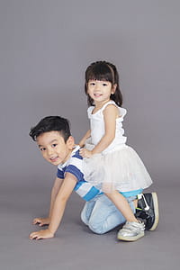 Girl in White Dress Sitting on Crawling Boy's Back thumbnail
