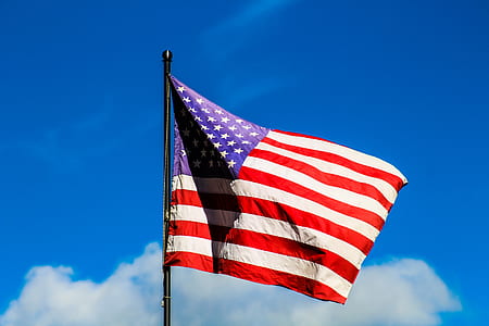 USA flag on pole under blue and white cloudy sky thumbnail