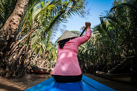 person paddling boat between palms thumbnail
