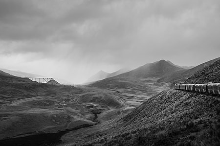 grayscale photo of train traveling a mountain thumbnail