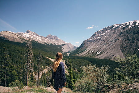 woman standing on cliff overlooking mountains during daytime thumbnail