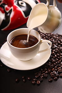 White Ceramic Pitcher With White Cream Pouring on Black Coffee Mug thumbnail