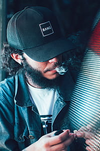 close view of man wearing black cap and smoking cigarette thumbnail