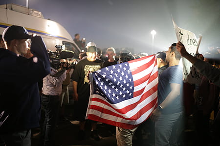man holding American flag surrounded with people thumbnail