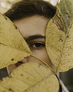 closeup photo of man covered his right eye with dried leaf thumbnail