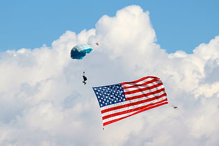 person skydiving with flag of USA during daytime thumbnail