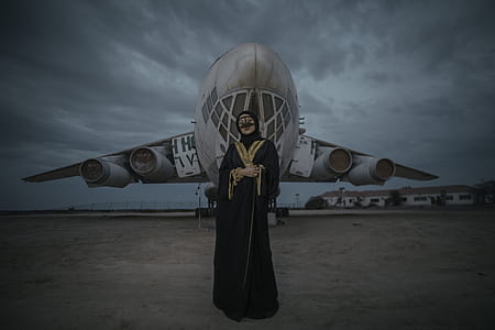 woman black abaya dress standing in front of airliner thumbnail