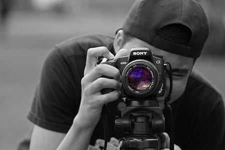 grayscale photography of man holding Sony DSLR camera thumbnail
