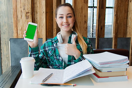Smiling Woman Holding White Android Smartphone While Sitting Front of Table thumbnail