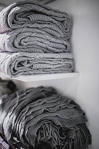 Folded sweaters and fabrics stacked on shelves thumbnail