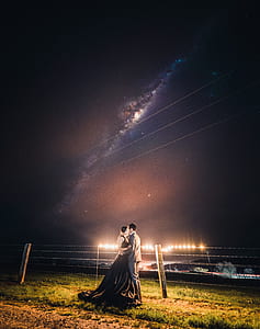 man and woman about to kiss standing beside fence thumbnail