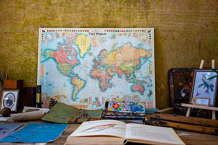 multicolored map poster beside flower framed painting and opened book thumbnail