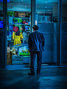 man and black top looking through glass wall of store thumbnail