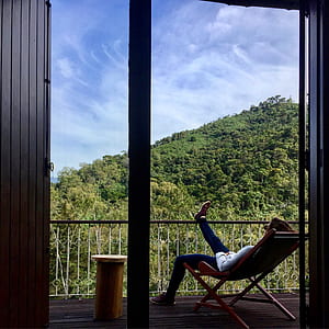 Person In White Long Sleeved Shirt Sitting On Folding Chair One Foot On Railings thumbnail