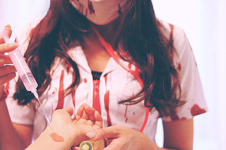 woman in bloody nurse uniform injecting human hand thumbnail