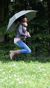 woman holding umbrella while jumping during daytime thumbnail