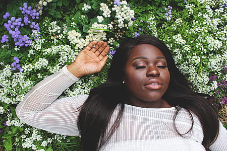woman with white long-sleeved top lying on white and purple petaled flower bed thumbnail