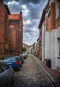 cars parked on side of pathway between houses thumbnail