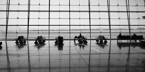 grayscale photo of person sitting overlooking glass window thumbnail
