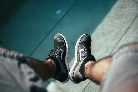 person wearing gray-and-black Nike sneakers sitting on concrete thumbnail