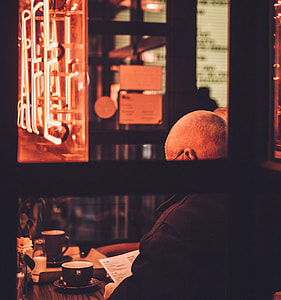 man wearing black top sitting at table looking at paper thumbnail