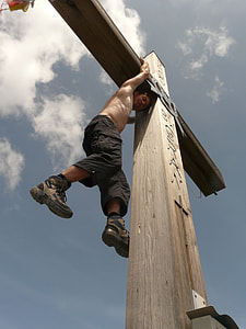 topless man hanging on wooden cross during day thumbnail