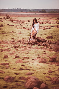 woman wearing white long-sleeved top sitting on rock thumbnail