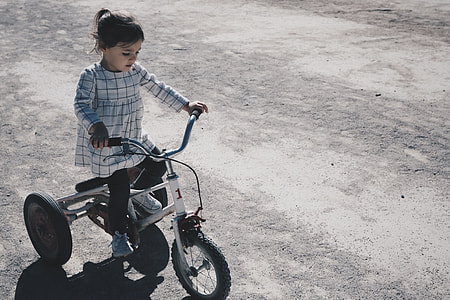 girl riding on white trike during daytime thumbnail