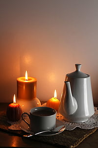 three orange candles beside teacup and teapot on brown mat thumbnail