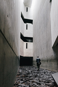 man walking between of gray concrete walls thumbnail