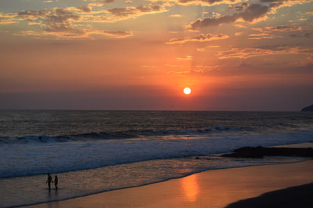 two people walking on beach during sunset landscape photography thumbnail