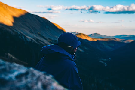 person wearing blue jacket standing on rock formation under white and blue sky thumbnail