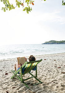 photo of woman reading book near seashore thumbnail
