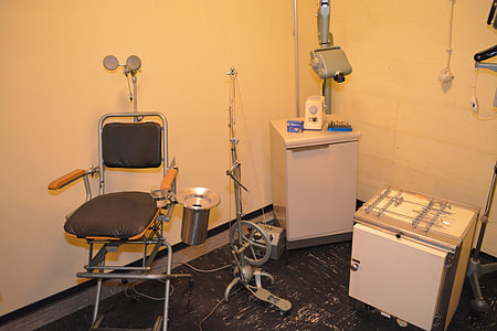 grey and black medical chair and white compact refrigerator thumbnail