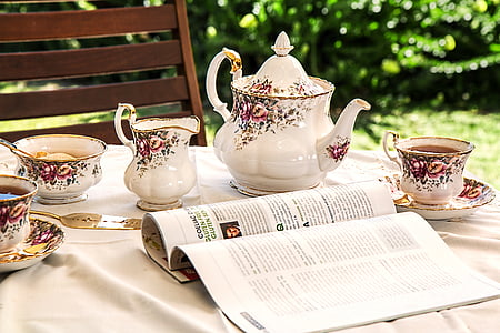 open magazine near white-and-pink floral tea set on top of table thumbnail