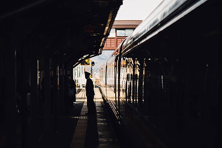 silhouette of man standing on train station platform thumbnail