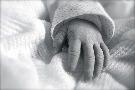 greyscale photography of baby's hand thumbnail