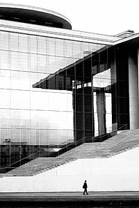 person walking beside white and glass building thumbnail