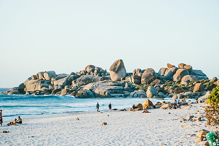 photo of people near shoreline and rock formations thumbnail