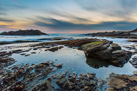 panning photography of clouds above rocks on body of water thumbnail
