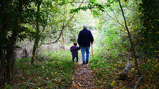 man and boy holding hands walking dirty pathway towards forest thumbnail