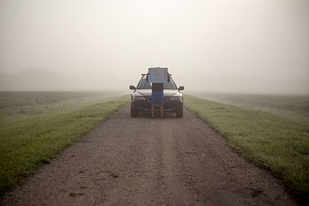 person standing on front of black car between green grass field thumbnail
