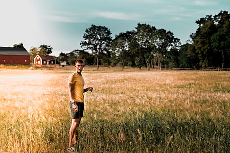 man standing on green grass field near house and trees at daytime thumbnail