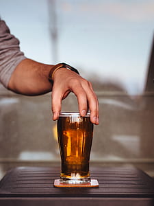 person holding beer glass on brown coaster thumbnail